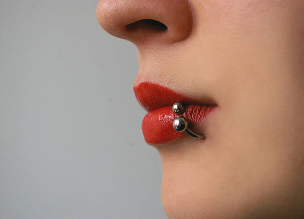 Close up on a woman's mouth Close up on a woman's mouth wearing red lipstick and has a piercing Pierced stock pictures, royalty-free photos & images