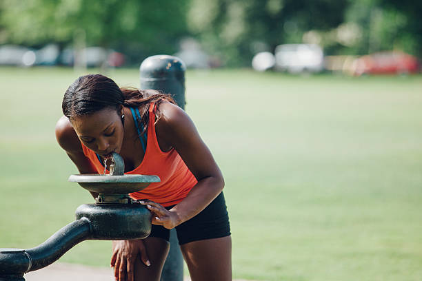 istock female jogger in city park drinking water 479400246