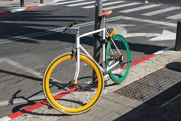 colored bicycle locked to a post on the pavement