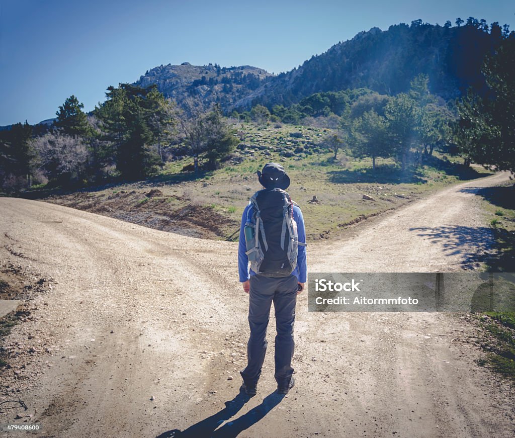 Man with two different ways Hiker man choose between to directions at the mountain Forked Road Stock Photo