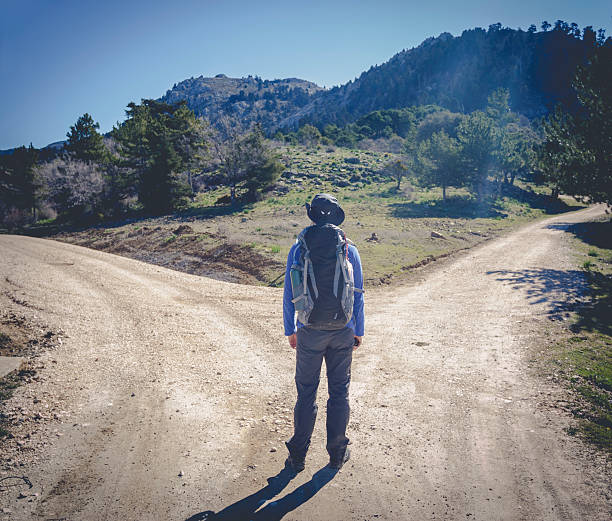Man with two different ways Hiker man choose between to directions at the mountain forked road photos stock pictures, royalty-free photos & images