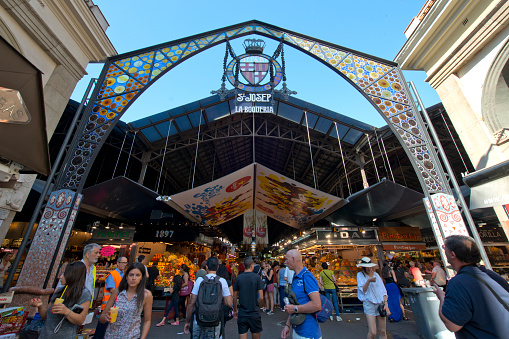 Barcelona, Spain - June 26, 2015: Tourists in famous La Boqueria market on June 26, 2015 in Barcelona. One of the oldest markets in Europe that still exist.
