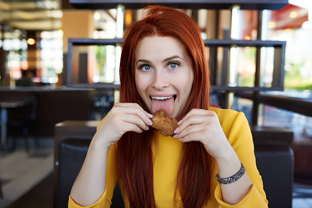 istock hungry woman with chicken drumsticks 479413204