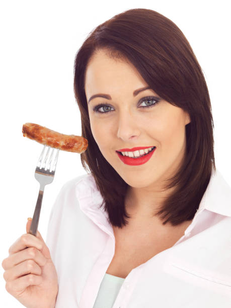 junge glückliche frau holding a cooked schweinefleisch wurst am fork - sausage grilled isolated single object stock-fotos und bilder