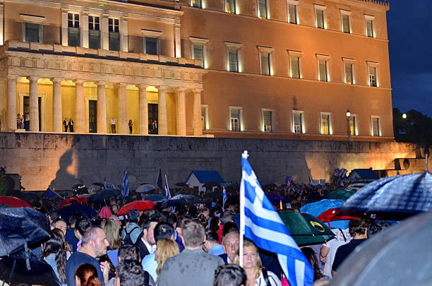 Silhouette of raised arms and clenched fists on the background of the flag of Greece. The concept of power, power, conflict. With place for your text.