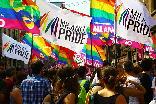 Milan, Italy - June 27, 2015: Multi colored flags waved by the numerous people attending the Gay Pride Parade. 