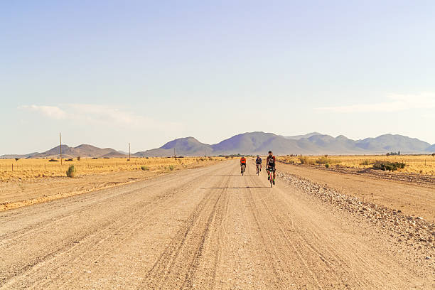 Solitaire, Namibia - April 25, 2015: Men on the bicycles cycling thru Namib desert landscape near Solitaire in Namibia.