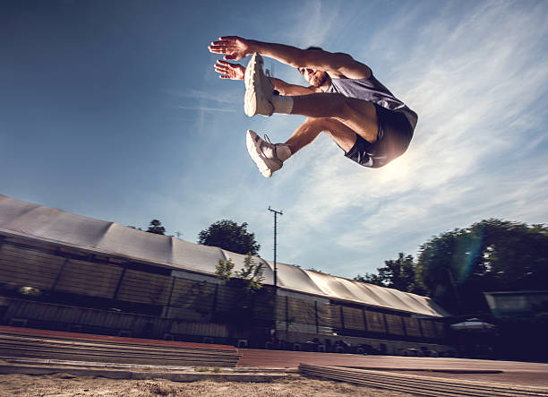 Below view of a young athlete in a long jump. Low angle view of young man in long jump. long jump stock pictures, royalty-free photos & images