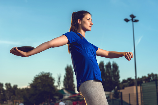 Athletic woman exercising throwing a discus.
