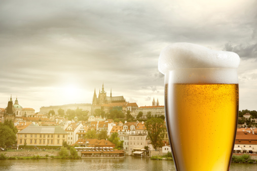 Glass of beer against view of the St. Vitus Cathedral in Prague