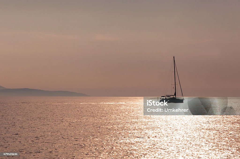 Sailboat on sunset A sailboat is cruising in the croatian sea on sunset. Coast of an island in the background. 2015 Stock Photo