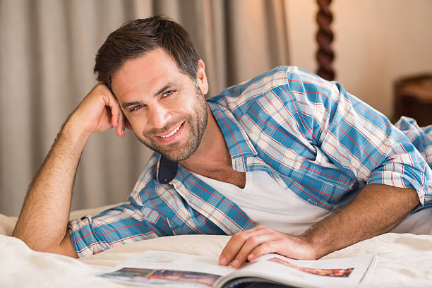 istock Handsome man relaxing on his bed reading magazine 479431738