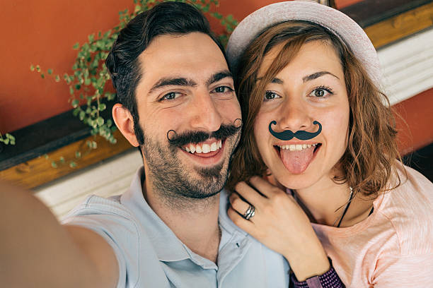 couple making selfie с mustaches - risible стоковые фото и изображения