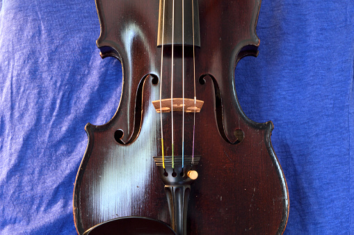 Vintage violin against blue linen.Violin is an antique from the early 1800's in a dark stain (original finish).