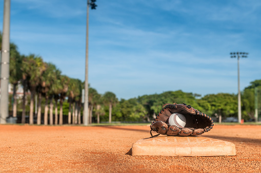 Baseball glove placed on third base ina a sunny morning