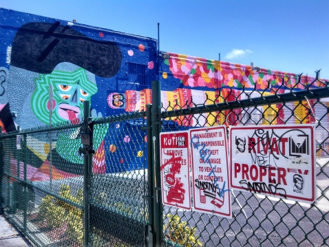 Miami, United States - February 22, 2014: In the Wynwood Arts District private properties are used as canvases for large scale murals. Gates secure the space and protect the art.