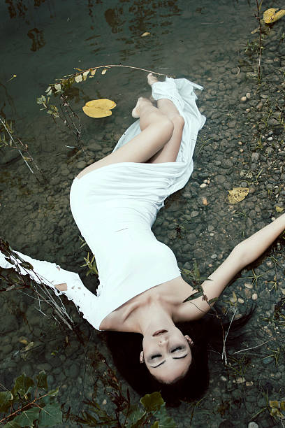     Woman lying on the shore in white dress, mystery scene 