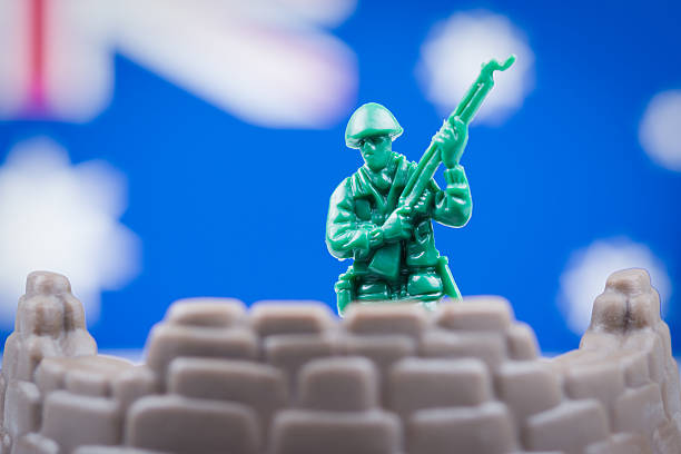 Plastic toy soldier stands in front of blurred out Australian flag.