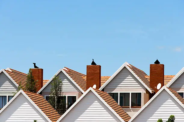 Close up detail of town house rooftops with chimneys against blue shy.