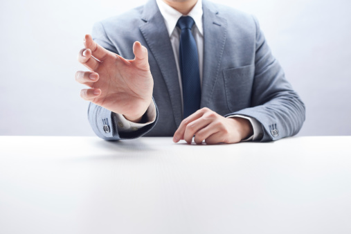 Front view of a businessman holding an invisible product at desk.