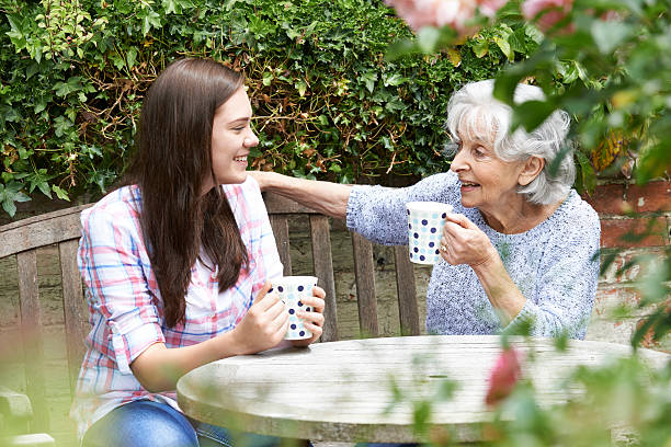 nastoletnie wnuczka relaksujący z babcia na ogród - coffee buzz zdjęcia i obrazy z banku zdjęć