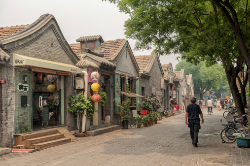 Beijing, China - June19, 2012: A man walks down the main street in the Jing Yang Hutong of Beijing. The Hutongs provide a glimps of life in Beijing centuries ago