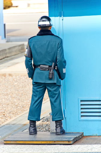 Panmunjom, South Korea - March 15, 2014: a South Korean soldier standing at a modified Te Know Do stance, called ROK Ready outside the conference building in Joint Security Area in Panmunjom. The young man stand half covered by the building and half exposed to the North Korean side, a symbol of being prepared to take cover if a fight breaks out, while being ready to fight at the same time.