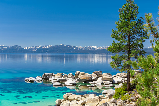 Photograph of Lake Tahoe near Sand Harbor. This is east shore line with many rocks and pine trees photographed in the morning during summer.