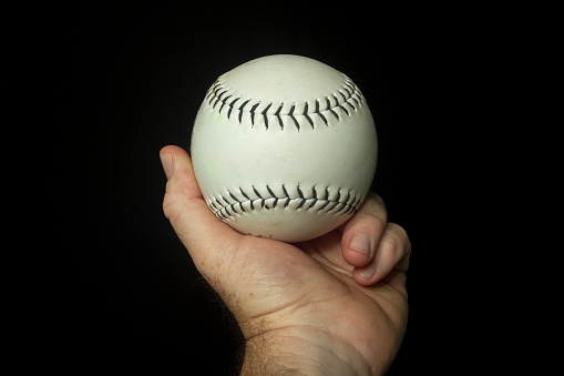 White softball in hand ready to throw.