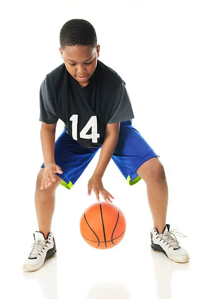 A preteen athlete rappidly dribbling his basketball close to the floor.  Motion blur on hands and ball.  On a white background.