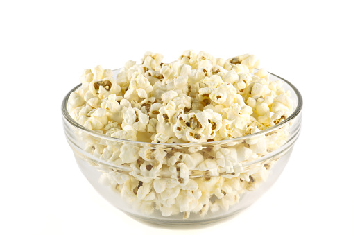 Popcorn in glass bowl on white background.