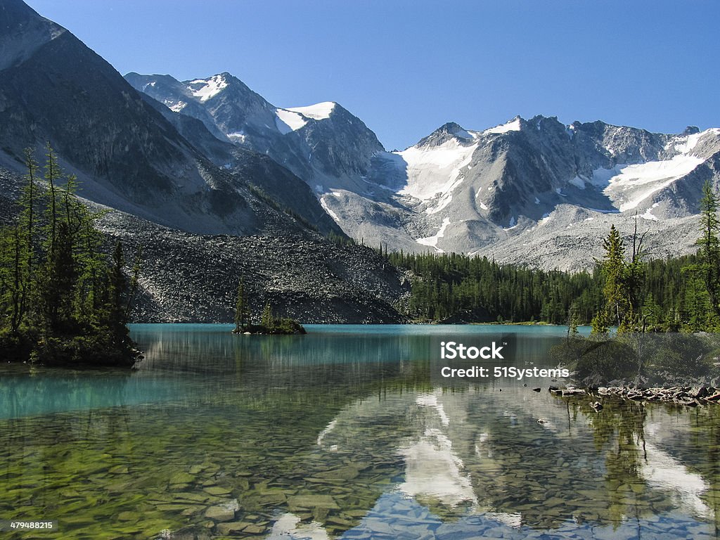 Alpine Lake A calm alpine lake with a small island Rocky Mountains - North America Stock Photo