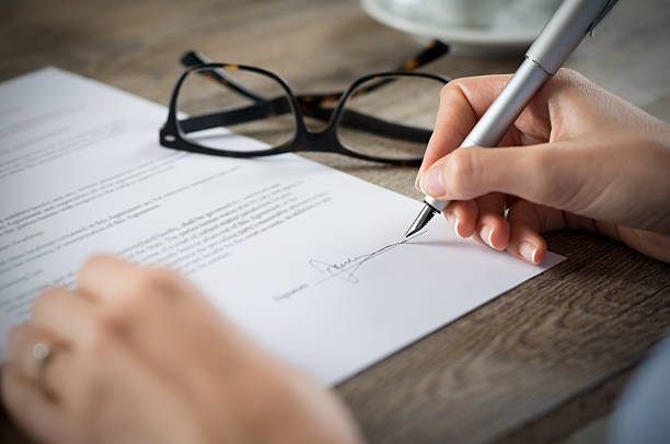 Signing a form Closeup shot of a woman signing a form. She's writing on a financial contract. Shallow depth of field with focus on tip of the pen. endorsing stock pictures, royalty-free photos & images