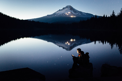 hiker on the shore of the lake during twilight, in the lake mountain reflects (Mount Hood in Oregon).