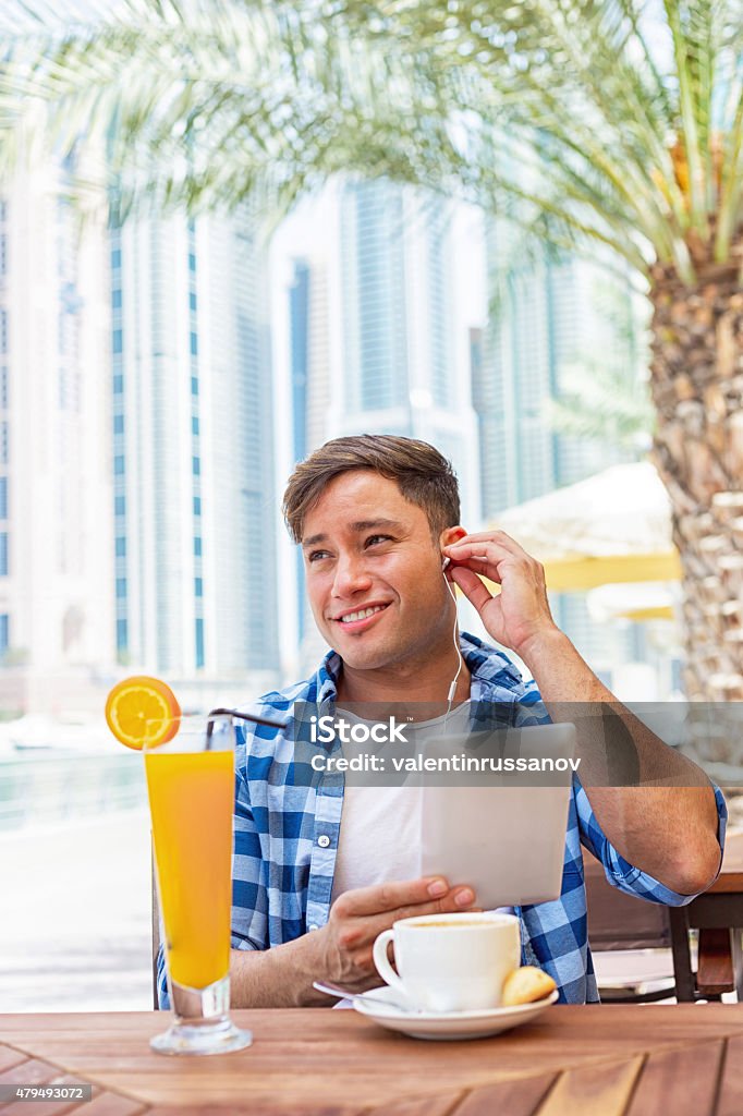 Young man drink coffee and using tablet in Dubay Young man drink coffee and using tablet in Dubay. Young man drink coffee in Dubai Marina.  iStockalypse Dubai - UAE 2015 20-24 Years Stock Photo