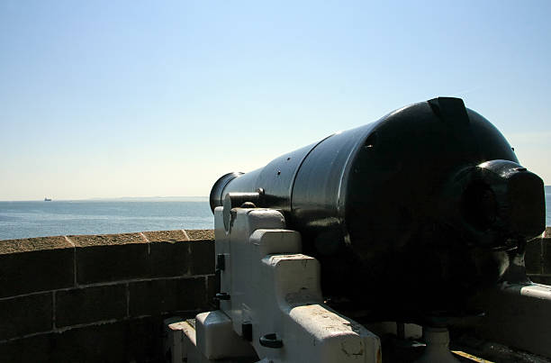 istock Antique cannon aiming at a ship on the sea 479493986