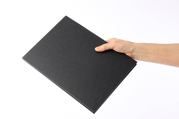 istock Holding a black blank book against white background 479496605