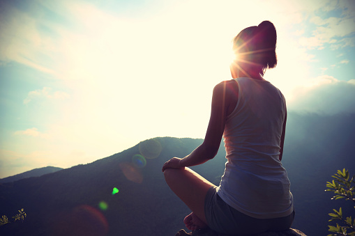 young yoga woman at sunrise mountain peak