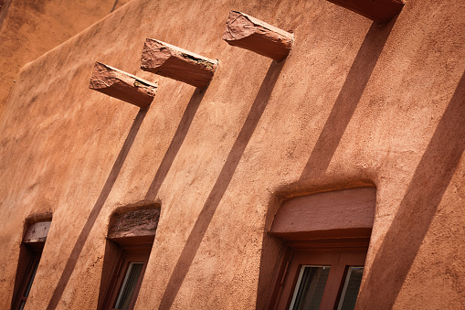 The American southwest adobe dwelling, a distinct style of architecture in the American southwest. A clay and straw fiber construction with exposed beams and rounded corners, in red brown earthen color. Photographed in Santa Fe, New Mexico, USA in a horizontal format.