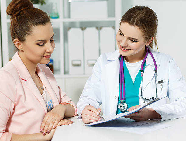 Signing treatment bill or insurance policy concept Beautiful smiling female medicine doctor holding clipped pad with document and pointing in it with pen to patient. Signing treatment bill or insurance policy concept recover tab stock pictures, royalty-free photos & images