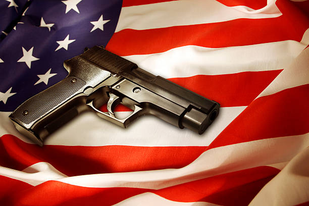 Gun Handgun lying on American flag gun control photos stock pictures, royalty-free photos & images