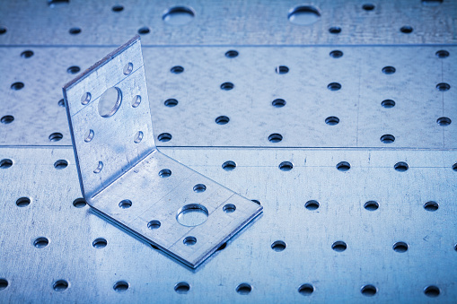 Drilled angle bar on perforated metallic texture construction concept.