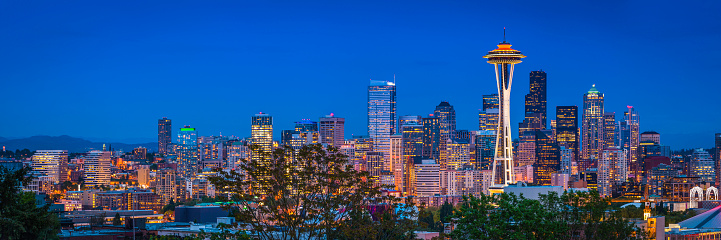 Panoramic view across skyline of Seattle, the iconic spire of the Space Needle and the crowded skyscrapers of downtown brightly illuminated against the blue dusk sky, Washington, USA. ProPhoto RGB profile for maximum color fidelity and gamut.