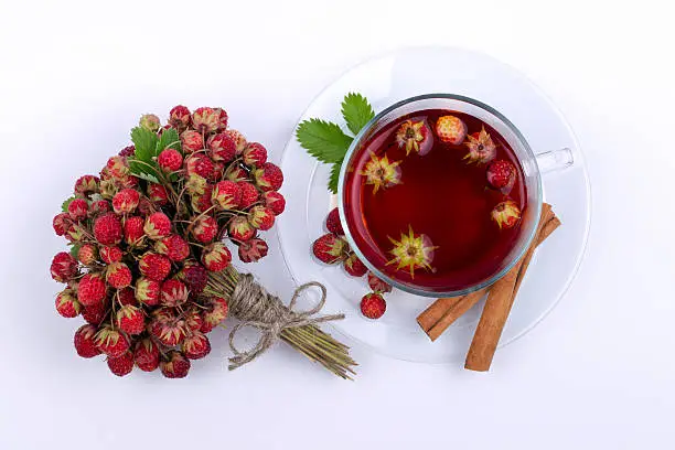 Fragrant bouquet of ripe wild strawberry and cup of fruit tea with cinnamon.