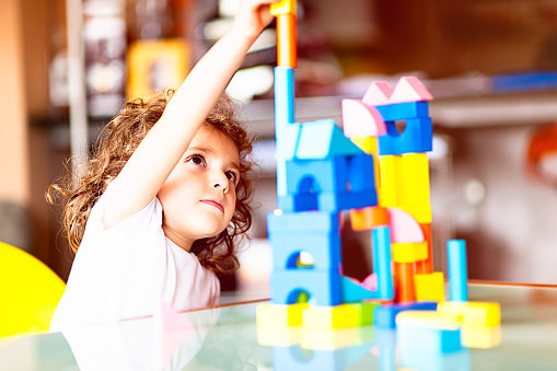Little girl building a house with cubes, indoors.