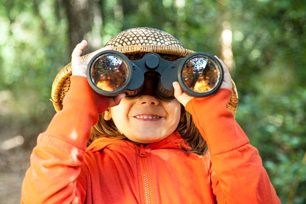 giovane ragazza guardando attraverso un binocolo - binocolo foto e immagini stock