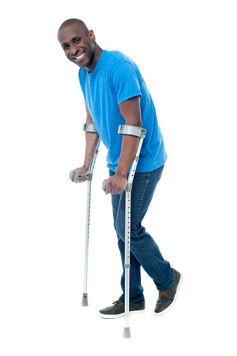 Happy middle aged man trying to walk with crutches