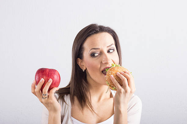 istock Young smiling healthy woman with apple and hamburger 479516257
