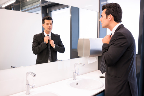 Portrait of handsome Mature adult man checking his hair and looking at his reflection in mirror