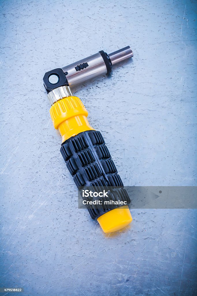 Metal reversive screwdriver with rubber handle on metallic backg Metal reversive screwdriver with rubber handle on metallic background construction concept. 2015 Stock Photo